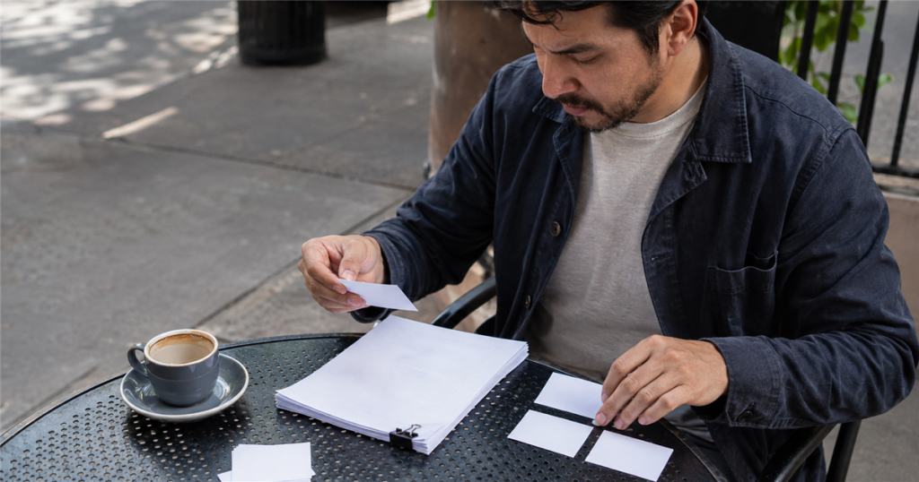 A writer sorts blank question cards beside a finished article.
